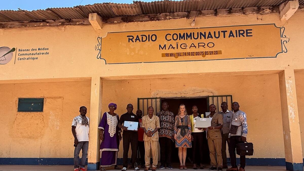 Des personnes se tiennent devant un bâtiment avec une pancarte qui indique Radio Communautaire Maigaro