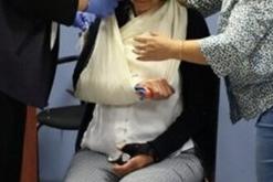 Two people assisting a person wearing a sling on their right arm.