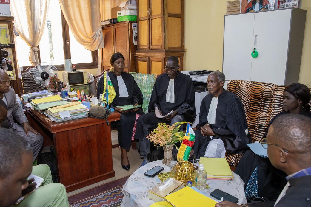 Des juges et un groupe de personnes sont assis dans un bureau et discutent.